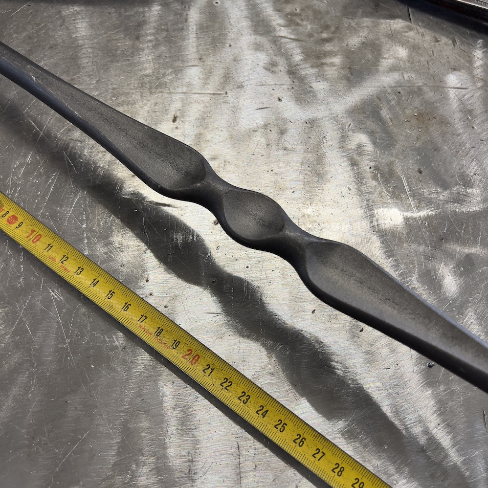 Barreau estampé motif aplati au centre avec équerre de rampe intégré, en fer forgé. Hauteur 1100mm rond lisse plein de diamètre 14mm, hauteur du motif 290mm, déport du barreau 65mm. Fixation par soudure. Fourni brut, à peindre ou à vernir pour protéger de la corrosion. Au delà de son rôle sécuritaire, il peut être un élément décoratif dans plusieurs réalisations en fer forgé tel que du mobiliers, divers objets décoratifs, des grilles de défense, des rampes d'escaliers, des portails, des kiosques, des gardes corps.