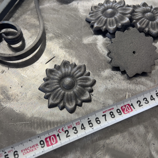 Rosace en fonte en forme de fleur. Diamètre de 85mm. Utilisation pour ornement de votre portail ou portillon, souvent en association avec une palmette. Fixation par vissage avec vis en M5, soit  Ø4,2mm, grâce à son taraudage M6 (vis non fournies). Fournie brut, à peindre ou à vernir avec des produits adaptés qui permettront sa protection contre la corrosion. La fonte est reconnue pour sa solidité, sa durabilité et sa résistance à la corrosion.